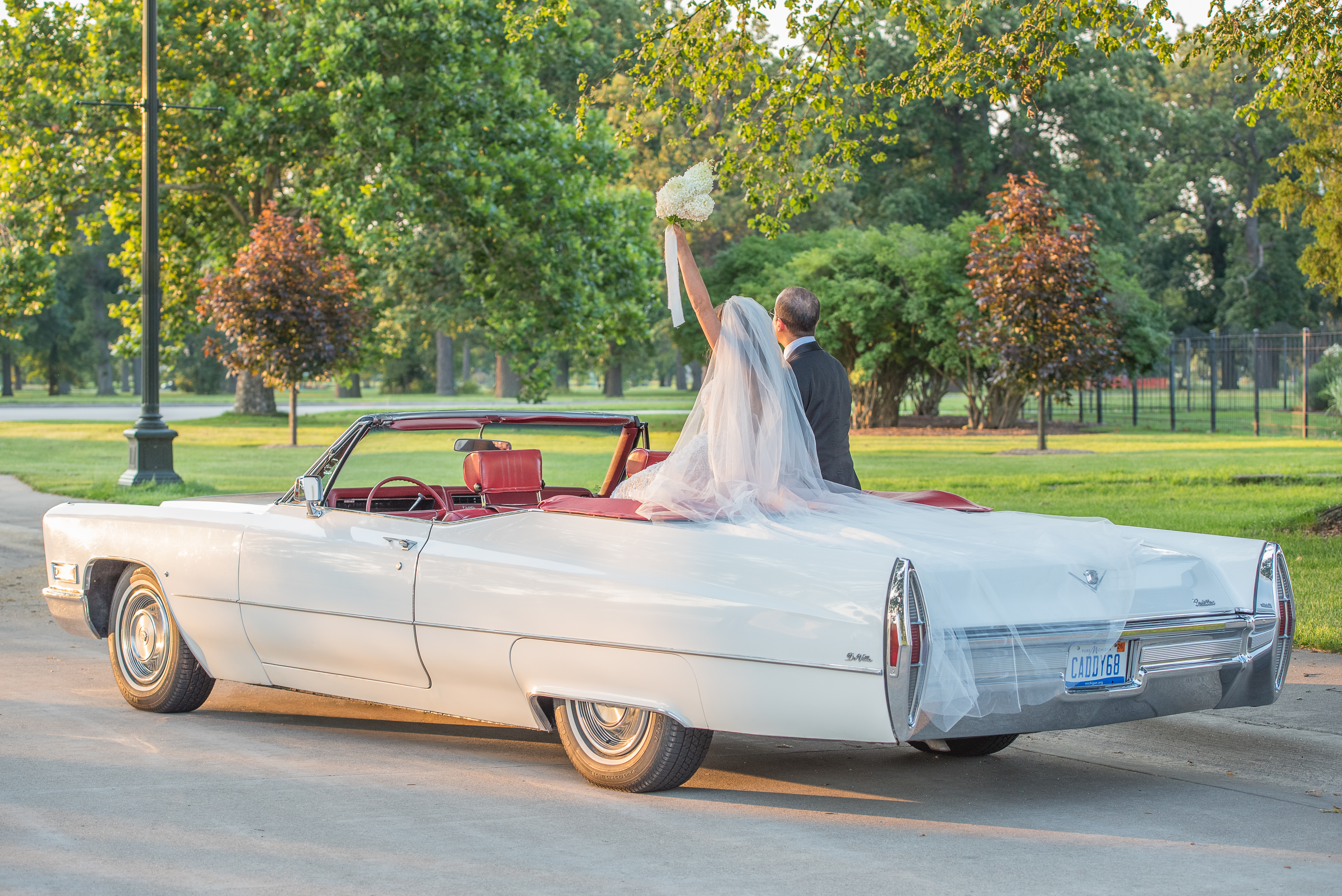 Bride and groom in vintage convertible Cadillac DeVille classic car.